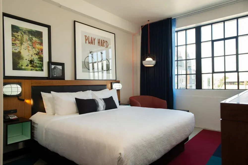 Hotel guest room at Indigo with headboard wall, nightstand cubes, sconces, and a pendant light