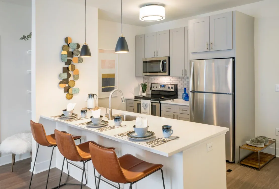 Apartment kitchen at Parc with gray cabinetry, peninsula seating, and cone pendants